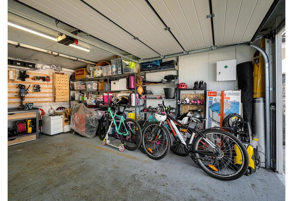 Vybavená montovaná garáž 4 x 6 m s policemi, nářadím a dílenským stolem.