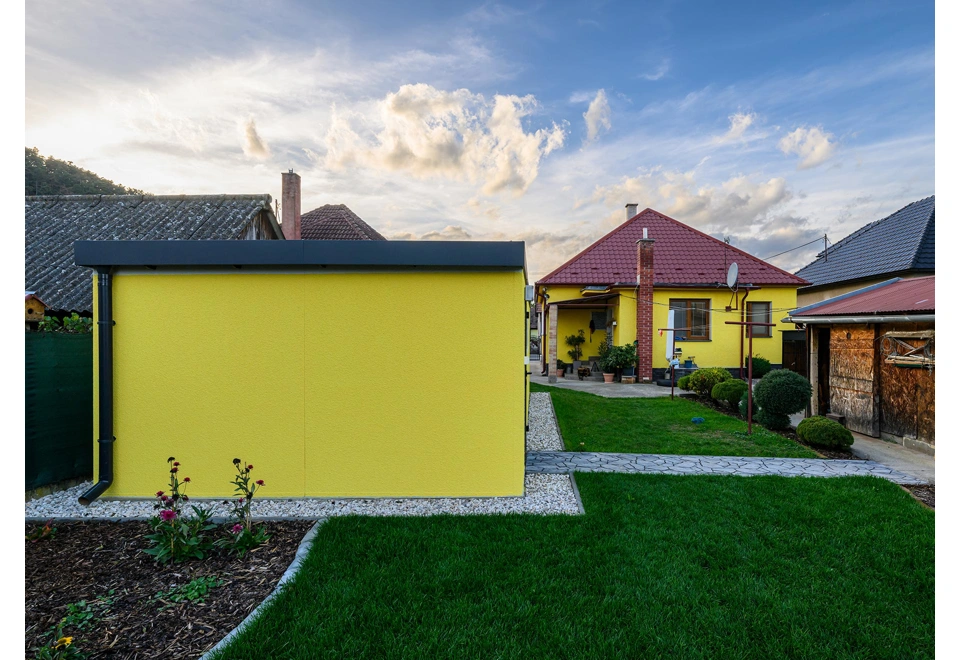Montovaná garáž 4 x 7 m s designovou žlutou omítkou, okapovým systémem a pultovou střechou.