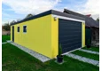 Montovaná garáž 4 x 7 m se žlutou omítkou, garážovými vraty, zateplenými dveřmi, dvěma okny a atikou v antracitové barvě.