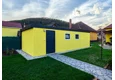 Montovaná garáž 4 x 7 m se žlutou omítkou, zateplenými dveřmi, dvěma okny a atikou v antracitové barvě.