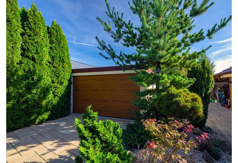 Montovaná garáž 4,5 x 7 m se žluto-pískovou fasádou a hnědými garážovými vraty a atikou.