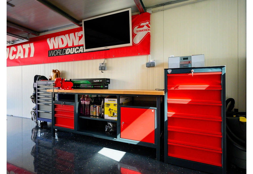 Dílenský stůl a skříňky montované garáže 3 x 7 m s bílými stěnami.