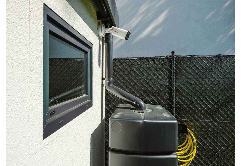 Okno a okapový systém montované garáže 3 x 7 m s bílou omítkou a černými doplňky.