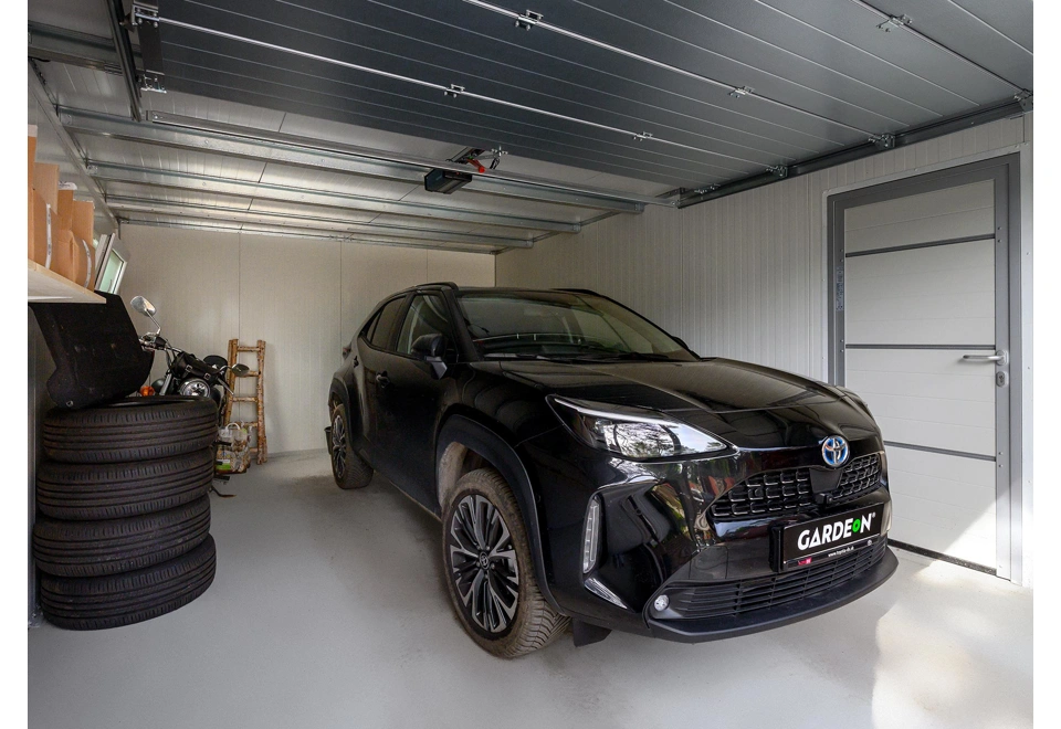 Interiér montované garáže 4 x 6 m s bílými stěnami a zateplenými jednokřídlými dveřmi.