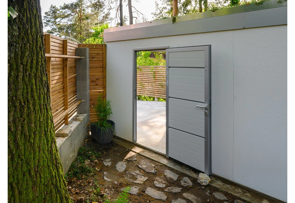 Izolované jednokřídlé dveře montované garáže 4 x 6 m se světle šedou omítkou a doplňky v barvě bílý hliník.