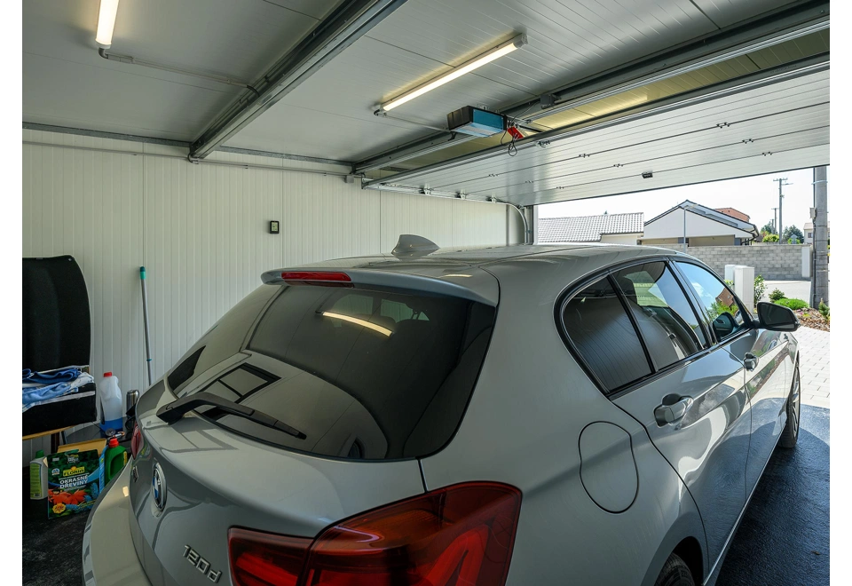 Interiér montované garáže 5,8 x 5 m s bílými stěnami a sekčními garážovými vraty.