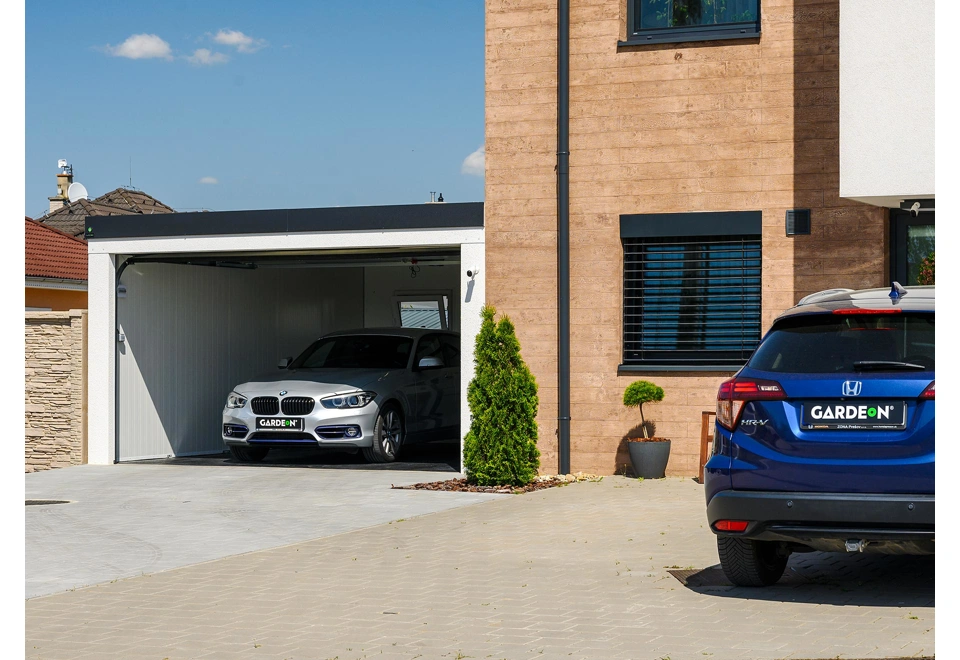 Otevřená montovaná garáž 5,8 x 5 m s bílou omítkou a vnitřními stěnami, oknem a atikou v černé barvě.