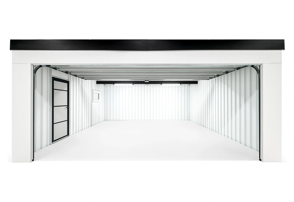 Interiér montované garáže 5,8 x 5 m s bílými stěnami a prázdným prostorem, jednokřídlé zateplené dveře.