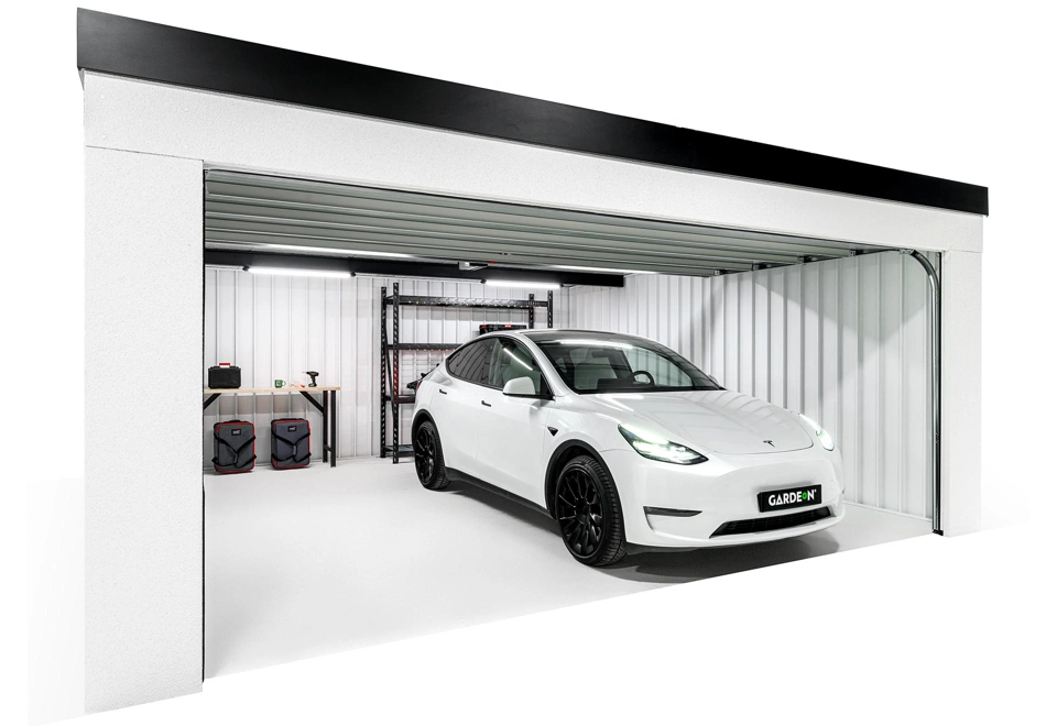 Interiér montované garáže 5,8 x 5 m s bílými stěnami, regálem a dílenským stolem.