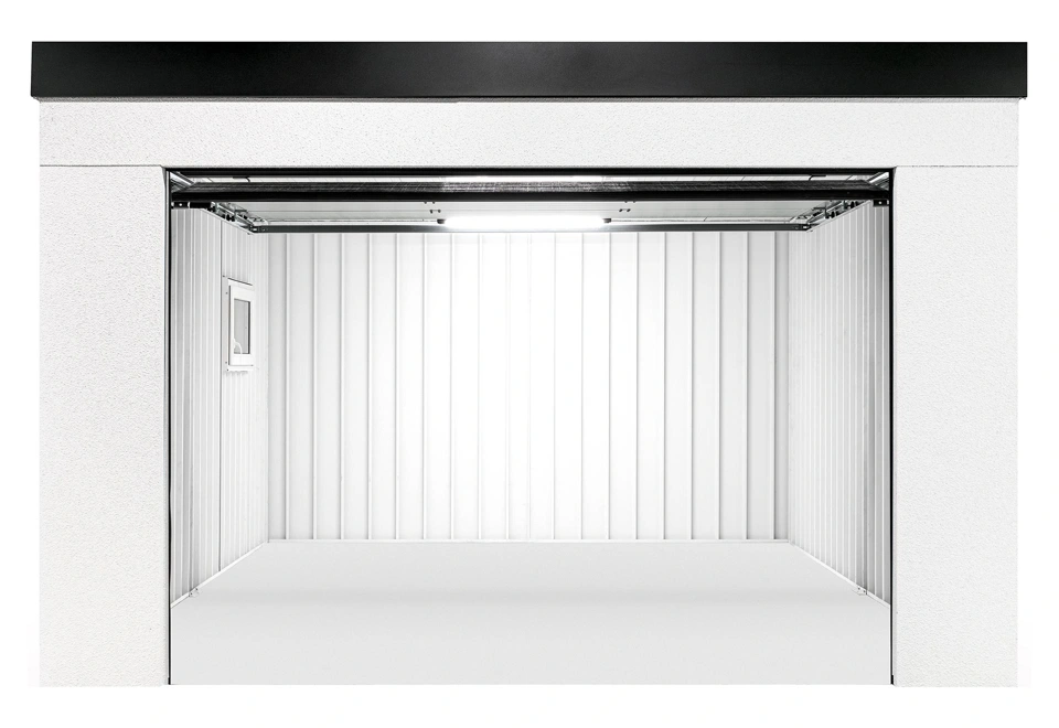 Otevřená montovaná garáž 4 x 5 m s oknem, bílou omítkou a doplňky v černé barvě, prázdný interiér s bílými stěnami.