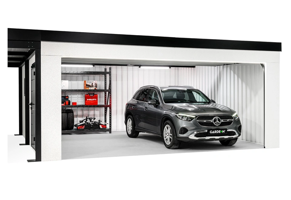 Otevřená montovaná garáž 5,8 x 6 m s bílou omítkou, zateplenými jednokřídlými dveřmi a přístřeškem na levé straně.