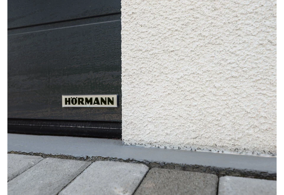 Detail designové bílé omítky a sekčních garážových vrat.