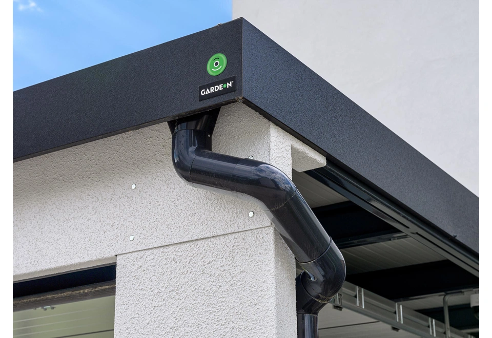 Detail černé atiky a okapového systému přístřešku 5 x 6 m s garážovými vraty.