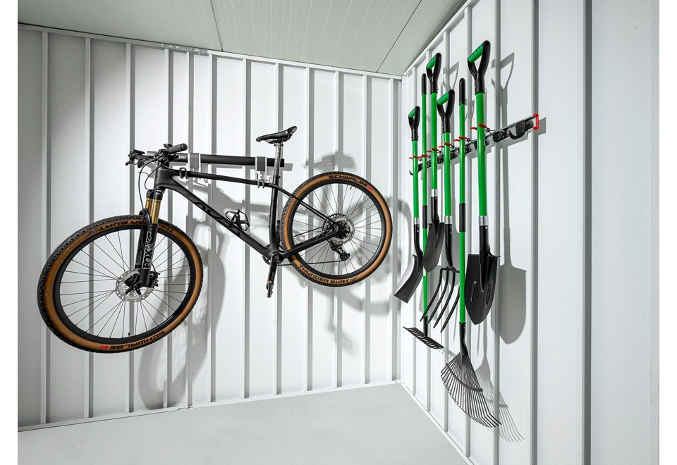 Interiér zahradního domku 3 x 2 m s držákem na kolo a nářadí, bílé stěny a zateplená střecha.