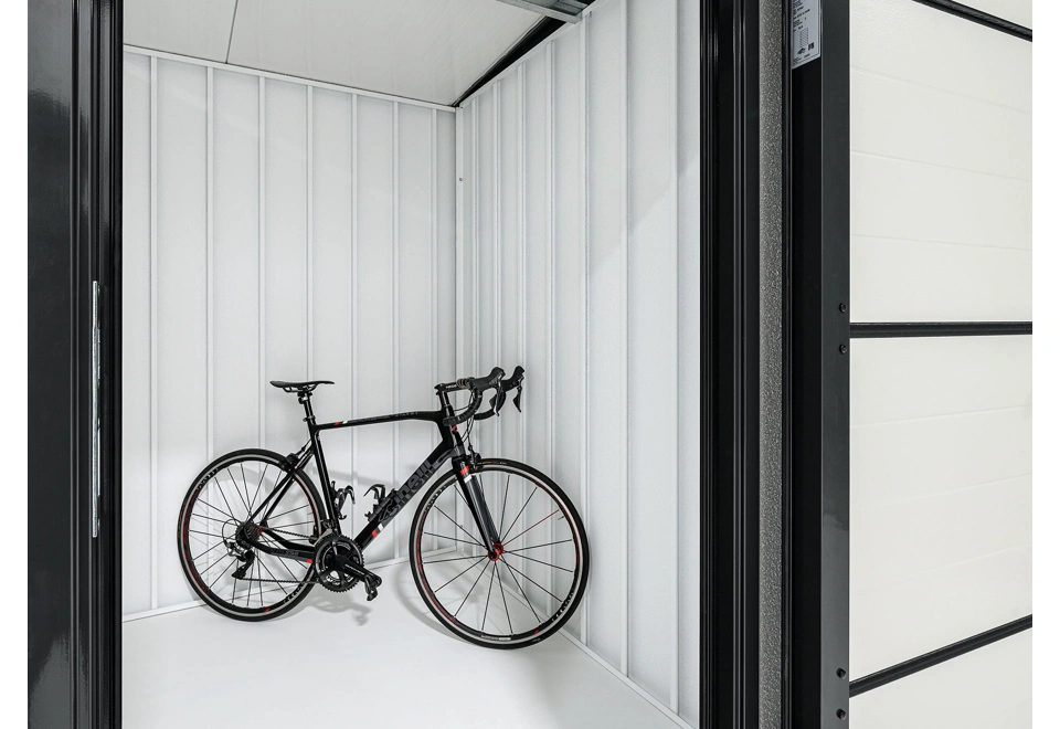 Interiér zahradního domku 2 x 2 m s kolem, bílými stěnami a zateplenou střechou i dveřmi.