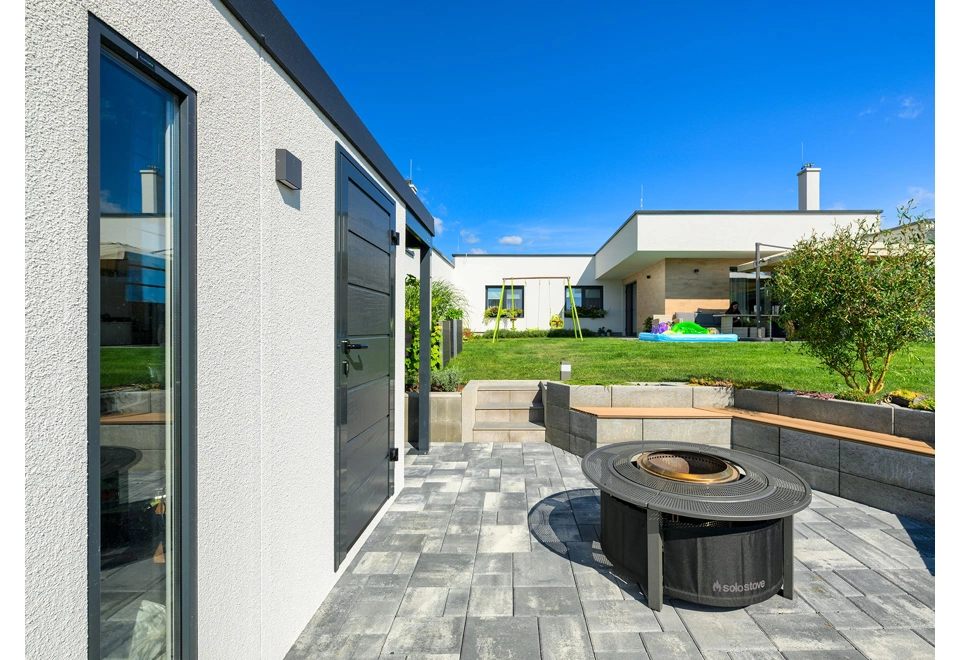 Světlík a zateplené dveře zahradního domku 3 x 2 m s pravým přístřeškem, bílá designová omítka a antracitové doplňky.