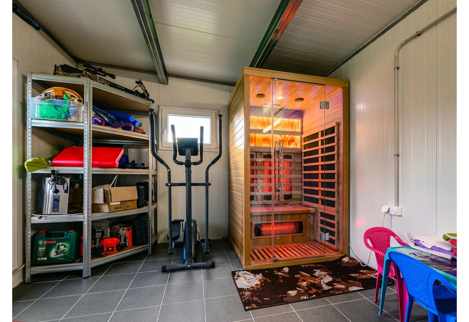 Interiér zahradního domku 5,8 x 3 m s oknem, vybavený infrasaunou a regálem