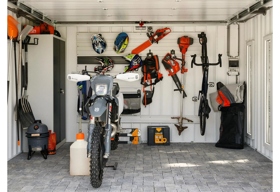 Interiér zahradního domku 4 x 3,5 m se závěsnými systémy na nářadí a sportovní vybavení, bílé stěny, zateplená střecha