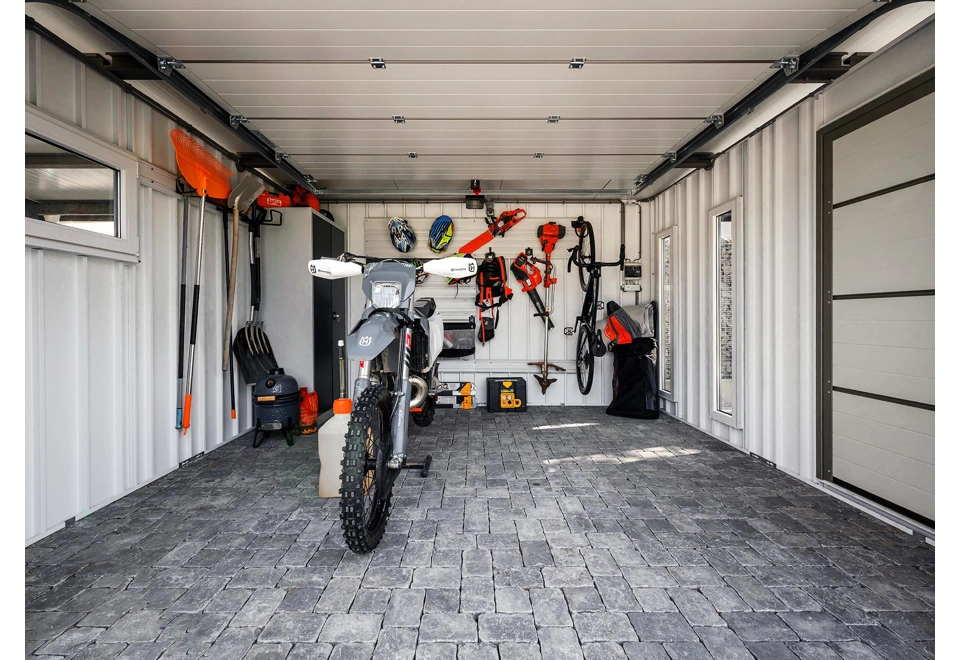 Interiér zahradního domku 4 x 3,5 m se závěsnými systémy, dvěma světlíky a oknem, bílé stěny, zateplená střecha i jednokřídlé dveře