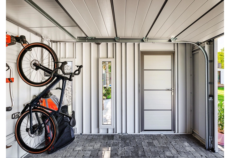 Interiér montovaného zahradního domku 4 x 3,5 m se dvěma světlíky, jednokřídlými dveřmi a garážovou bránou, bílé stěny a zateplená střecha