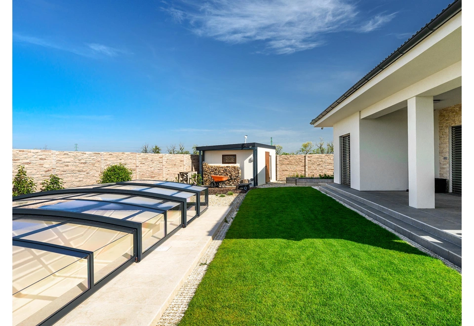 Zahradní domek 4 x 3 m s levým přístřeškem, oknem, jednokřídlými dveřmi, bílou omítkou, antracitovými a hnědými doplňky.