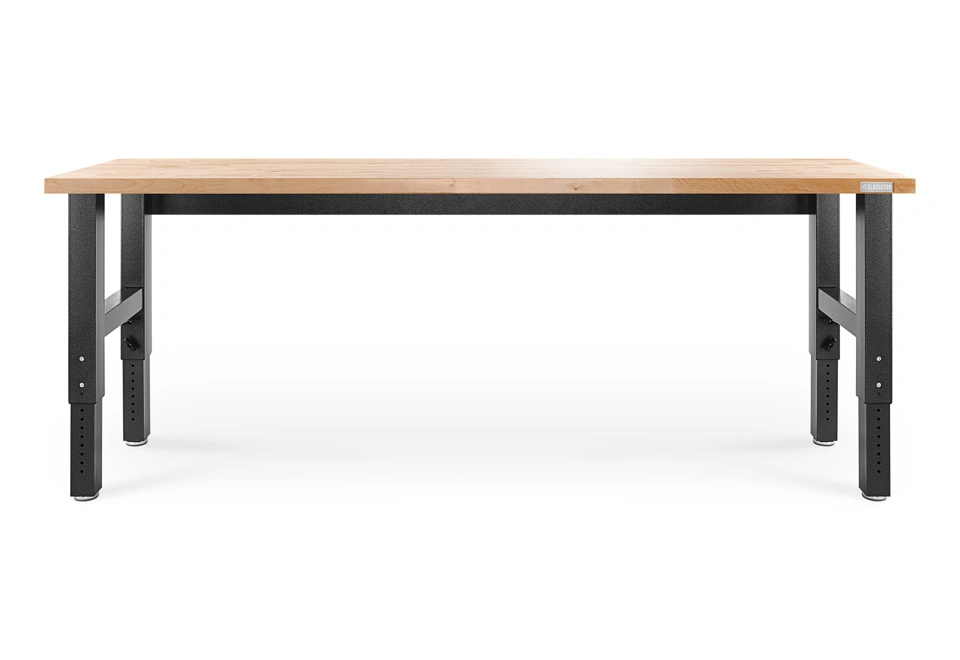 Dílenský stůl s deskou z masivního dřeva a výškově nastavitelné ocelové nohy.