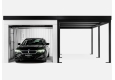 Otevřená montovaná garáž 3 x 6 m pro jedno auto, s bílými stěnami, oknem a zateplenými dveřmi, bílá omítka a doplňky v černé barvě, pravý přístřešek.