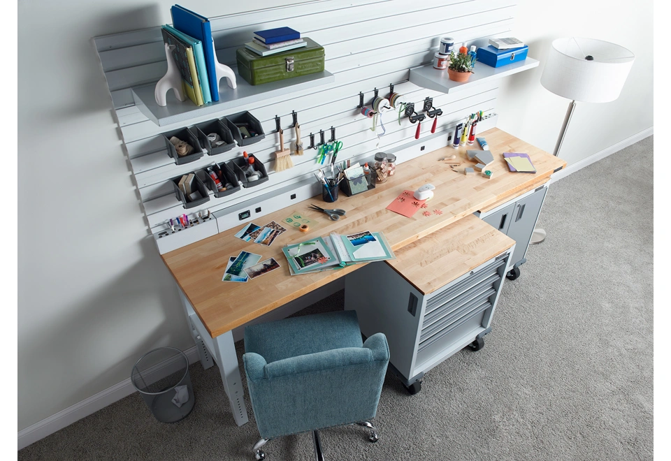 Šest zavěšených boxů na drobné předměty umístěných nad dílenským stolem.